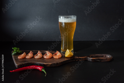 A glass of light beer on the table. Beer on a black background. Beer and shrimp on the table.