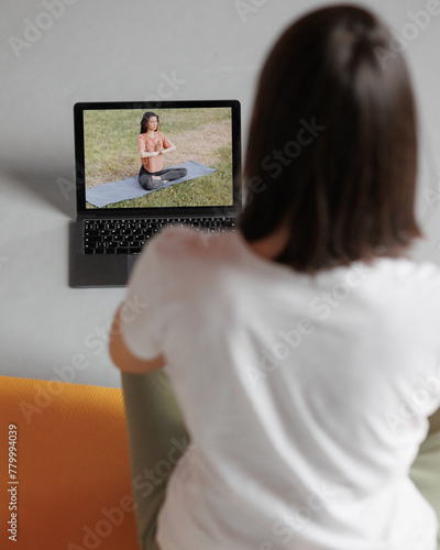 young woman practicing yoga at home, online video training. female performing exercises and meditation with trainer on internet. Yoga, balance and meditation, relaxation, healthy lifestyle concept