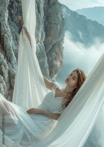 Une belle femme allongée dans un hamac en tissu blanc sur fond de montagnes brumeuses. photo