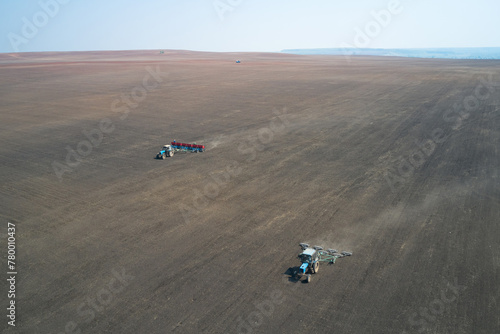 Sowing campaign. Sowing wheat in the field. Behind the tractor with a seeder works tractor with rollers. Shooting from a drone.