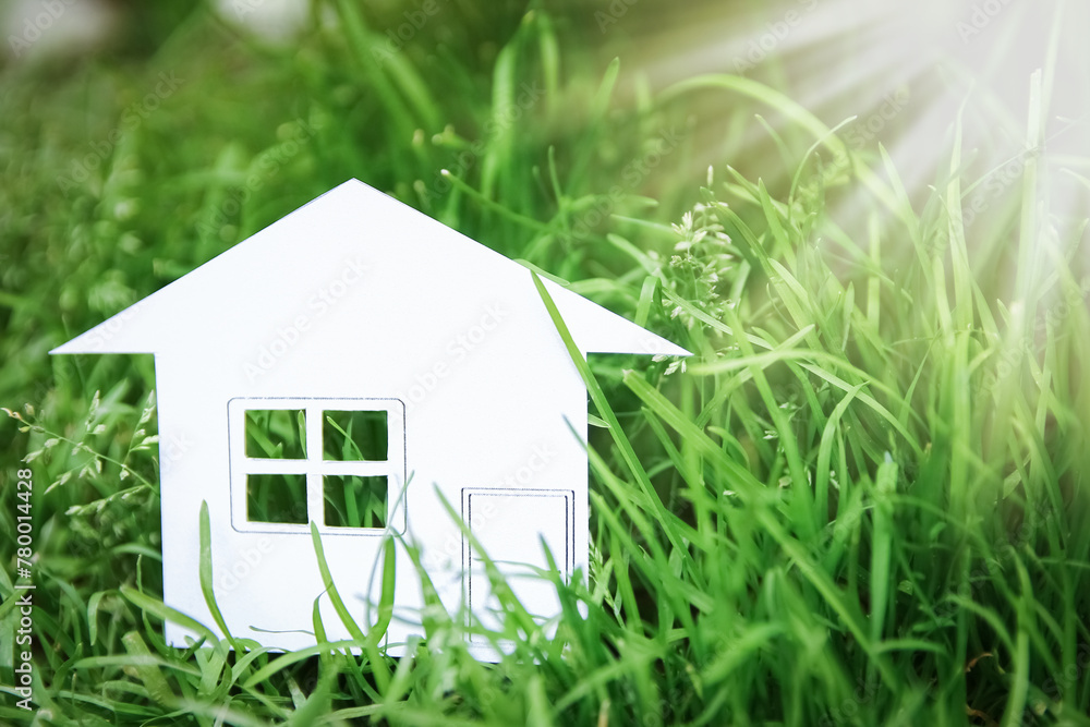 The concept or conceptual house white paper in his hand in a green summer grass on a background, a symbol for the construction, environment, credit, property or home