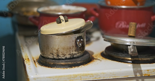 Poor dirty kitchen cooking in a cheap aluminum pan. Points to the pan.