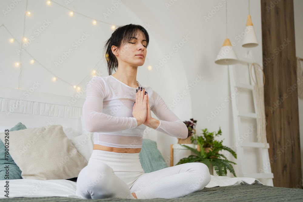 Yoga mindfulness meditation. Young healthy woman practicing yoga in bedroom at home. Woman sitting in lotus pose on bed meditating smiling relaxing indoor. Girl doing breathing practice. Yoga at home Yoga mindfulness meditation. Young healthy woman practicing yoga in bedroom at home. Woman sitting in lotus pose on bed meditating smiling relaxing indoor. Girl doing breathing practice. Yoga at home