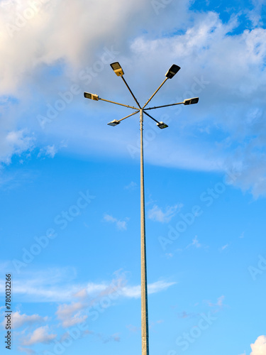 A pillar of street lighting with several lanterns against a gray sky. The concept of urban infrastructures in electric lighting. Electrical fittings with a system for increasing light in the dark.