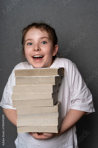 Happy teenage girl holding a big stack of books. Concept of knowledge with pleasure. High quality photo photo