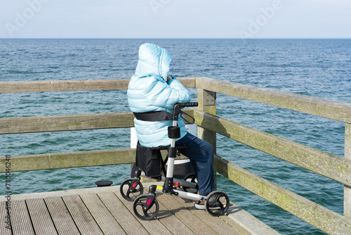 Elderly woman in a wheelchair enjoys the day by the sea. Peace, dreams and memories. Older people, Alzheimer's, depression and the end of life. Loneliness in old age.