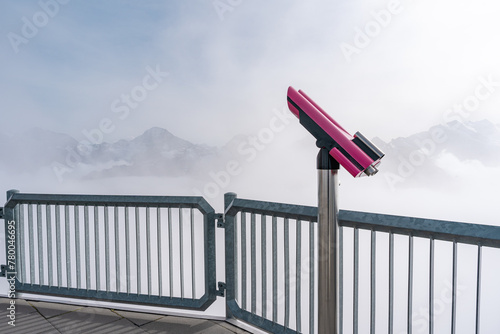 Pink tower viewer binoculars on top of a mountain  in Switzerland. View of Swiss Alps. Copy space on the left