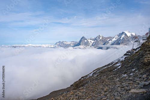 Obraz na płótnie View of Swiss Alps over clouds on a bright sunny day from Schilthorn summit in Switzerland. Cable car pylon w salonie
