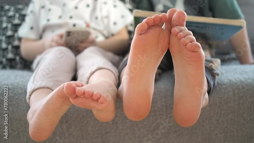 Big brother and little sister holding bare feet close up to camera . Blurred face on background  photo