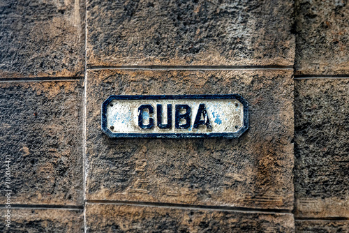 In the streets of Old Havana, Cuba, a street sign bearing the inscription "Cuba" stands against a rugged wall, exemplifying authentic vintage design, ideal for conceptual and travel-themed projects.