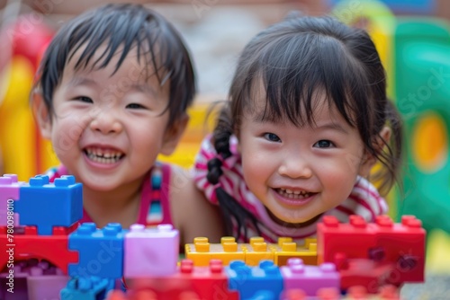 Two children happily playing with a colorful building set, stacking and creating various structures together in a joyful and imaginative way