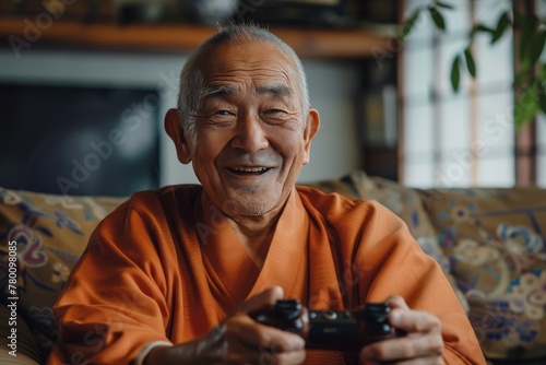 Smiling elderly monk in orange robe holding game controller. Cheerful senior monk engaging with modern technology through video gaming.