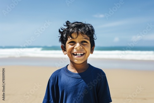 A young boy stands proudly atop a sandy beach, his eyes filled with wonder and excitement as he surveys the vast expanse of ocean before him