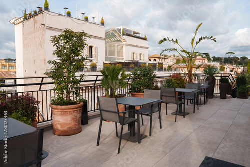 Explore a luxurious rooftop terrace in Rome with modern outdoor furniture, lush greenery, and panoramic views of the historic city skyline. Ideal spot for tourists.