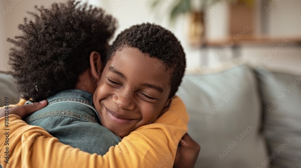 Fototapeta premium Father hugging son sitting on the sofa in a modern environment, Father's Day concept.