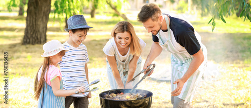 Happy family cooking tasty food on barbecue grill outdoors