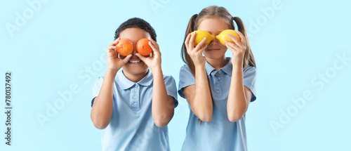 Happy little children with fresh citruses on blue background