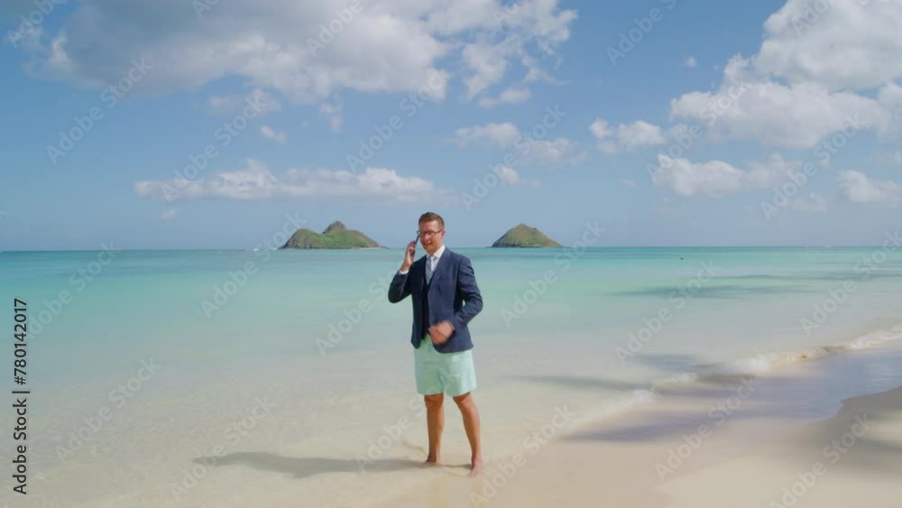 Handsome tall confident businessman making a call standing barefoot on white sand washed by iconic crystal waters of the Pacific ocean in Hawaii island. High quality 4k footage Handsome tall confident businessman making a call standing barefoot on white sand washed by iconic crystal waters of the Pacific ocean in Hawaii island. High quality 4k footage