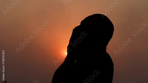 A Muslim old man praying with his hands raised to the sky in the afternoon twilight.