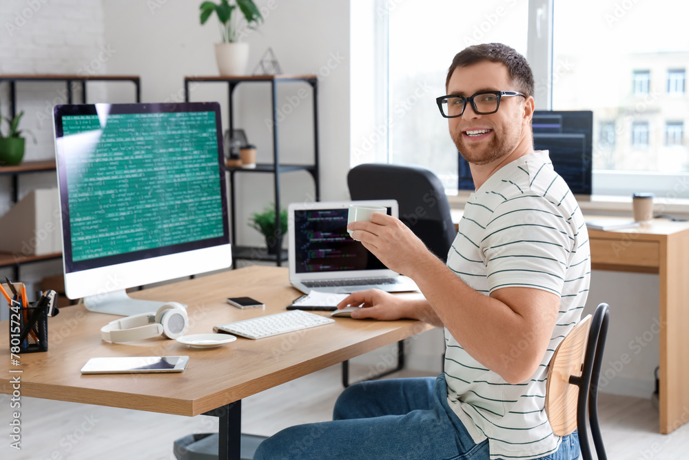 Portrait of male programmer with cup of coffee working in office