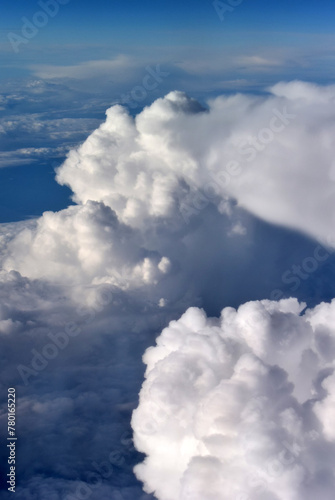 Vertical photo. Bird's eye view. High nature view of white fluffy big large soft clouds on blue sky from an airplane window in morning. Concept of travel, tourism, plane, trip, aircraft. Sunny day © brajianni