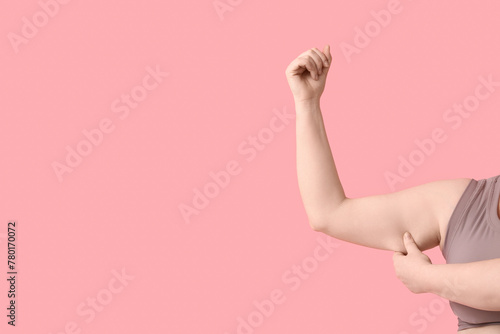 Arms of overweight woman on pink background. Diet concept photo