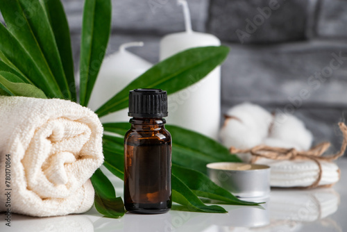Essential oil, towel and candles on gray stone background. Spa wellness accessories and cosmetics.