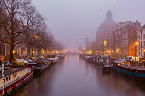 Amsterdam canal Singel with typical dutch houses during morning blue hour, Holland, Netherlands.