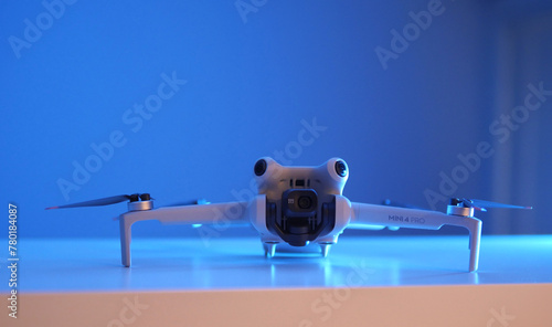 Unfolded DJI Mini 4 Pro drone on display in frontal view  against a blue background