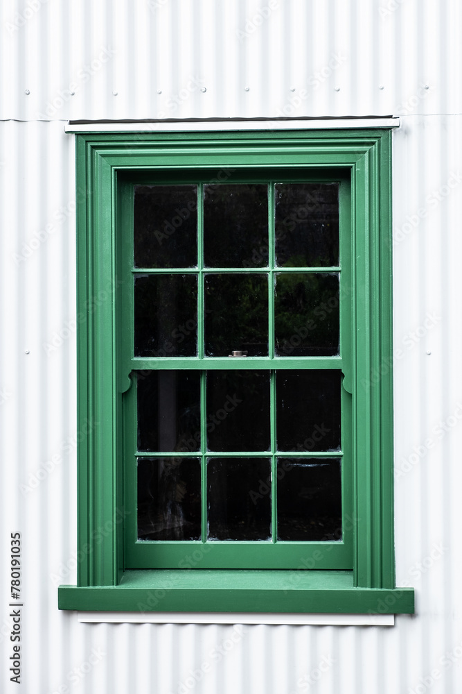 Old green sliding sash window on a white wall