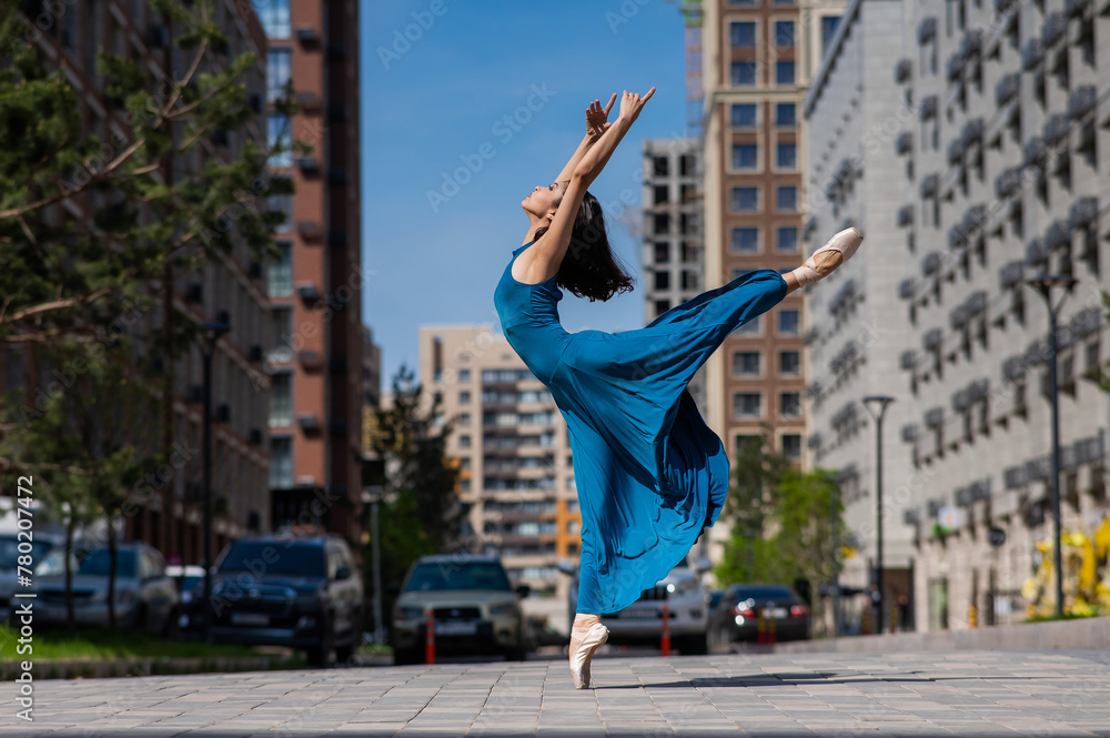 Beautiful Asian ballerina in blue dress dancing outdoors. Urban landscape.