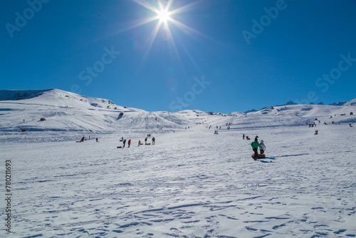 People riding downhill on tubing and sledding in the mountains in winter on a sunny day off