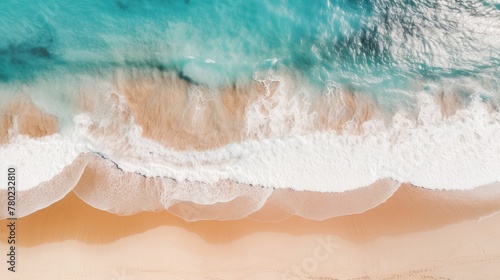 aerial view of the sea waves background rolling onto a pristine sandy beach, capturing the natural beauty of the coastline, sunlight creating a shimmering effect on the water