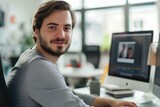 young content marketing consultant working at a computer in a modern office. he is looking at the camera and smiling. generative AI