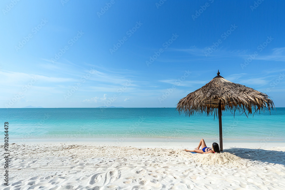Woman lies on sandy beach under straw umbrella. Photo from behind. The concept of summer holiday by the sea.