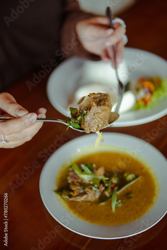 Oseng Mercon Person Eating Bowl of Soup With Spoon
