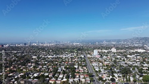 Aerial push in drone shot over Larchmont neighborhood during early morning. Street views down below. Beautiful blue sky above with  wispy clouds. photo