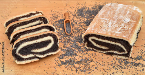 Homemade poppy seed roll with wooden scoop and poppy seeds on the wooden board. Selective focus.