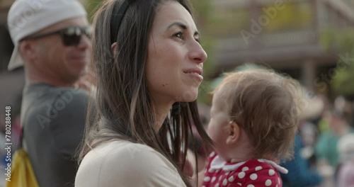 Mother super interested in outdoor parade event with daughter in arms