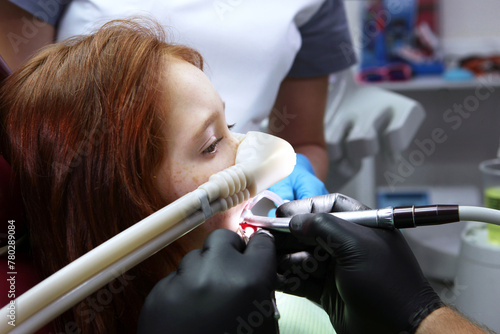Dental treatment in a child with sedation. A little girl is injected with an inhalation sedative during dental treatment at a dental clinic. Side view.