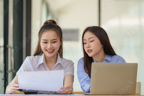 Two Asian businesswomen discuss new startup project idea presentation and analyze planning and financial statistics and investment market at the office.
