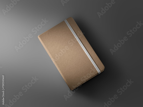 Mockup of closed craft notebook, diagonal top view, with white elastic band, textured hard cover, shadows on background.