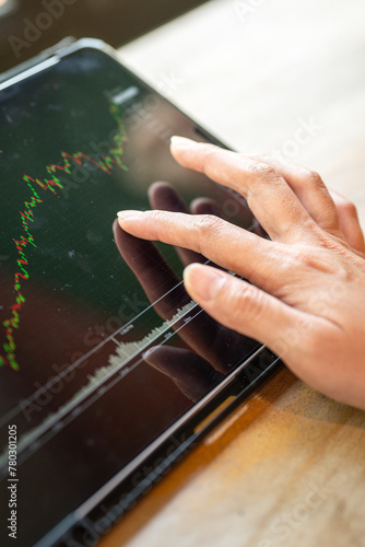 Action of an investor hand is touching on tablet displat to review the stock investment value graph. Business investment scene photo, close-up and selective focus. photo