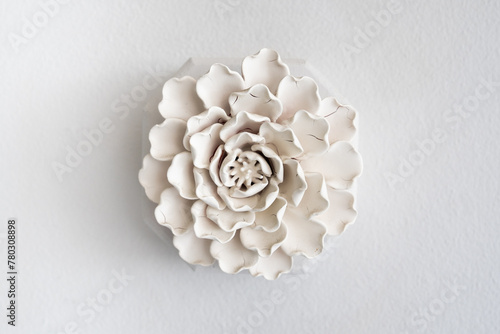 Elegant white ceramic flower sculpture mounted on a wall providing a minimalist and artistic decor element for modern interior
