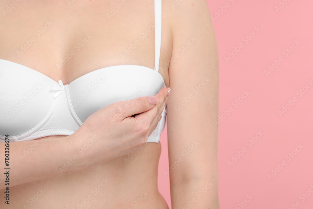 Mammology. Young woman doing breast self-examination on pink background, closeup. Space for text
