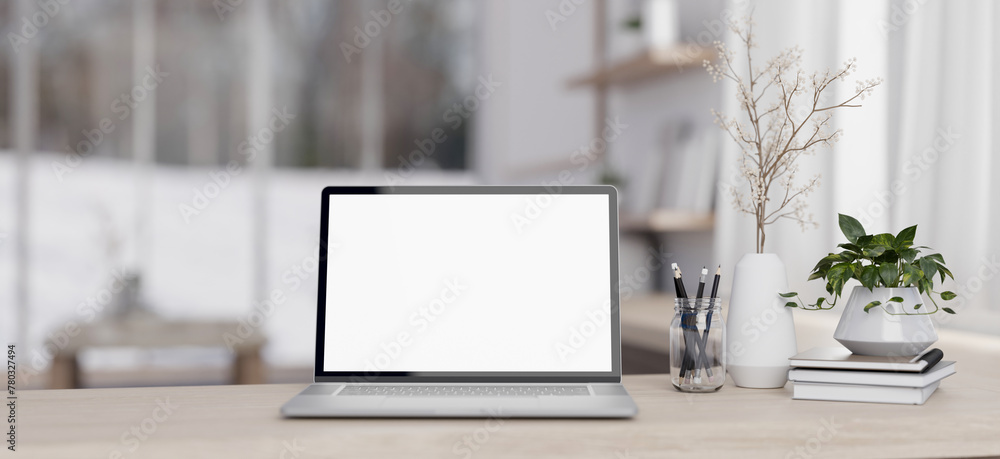 A laptop computer mockup and decor on a minimal wood table in a contemporary white living room. A laptop computer mockup and decor on a minimal wood table in a contemporary white living room.