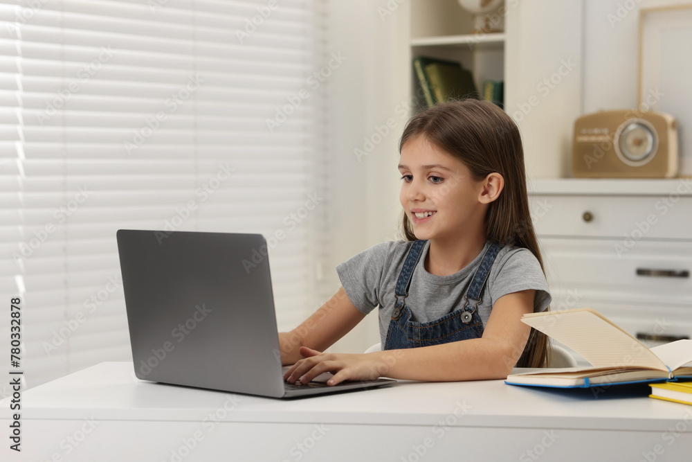 Cute girl using laptop at white table indoors Cute girl using laptop at white table indoors