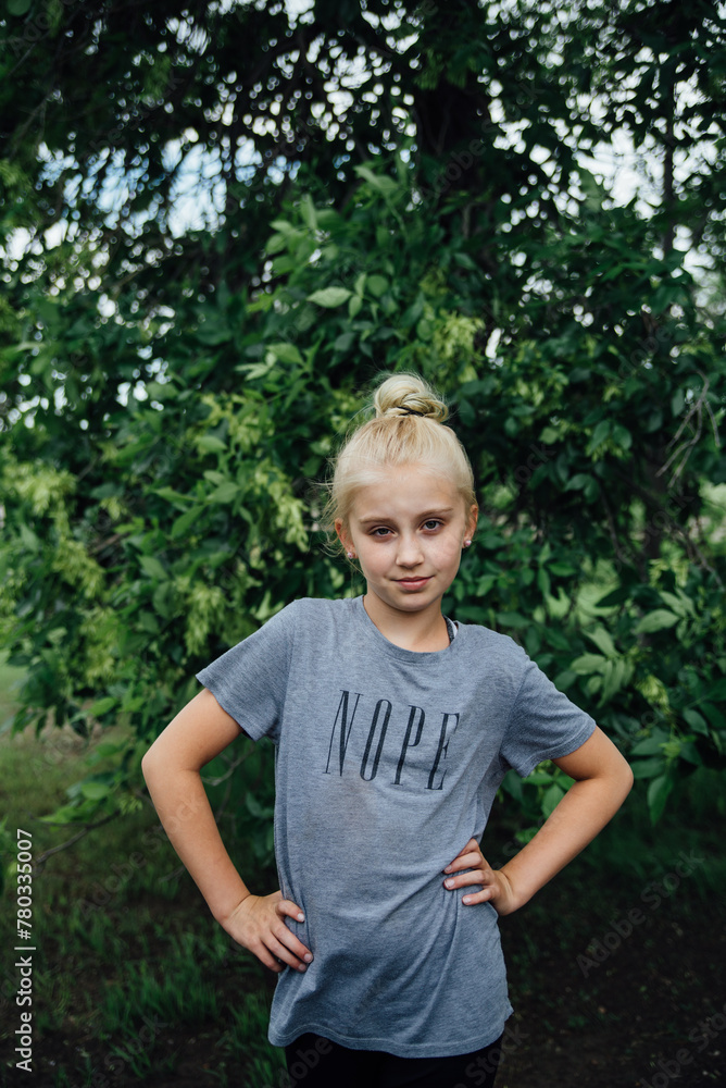 Preteen girl with attitude stands with hands on her hips outdoors Preteen girl with attitude stands with hands on her hips outdoors