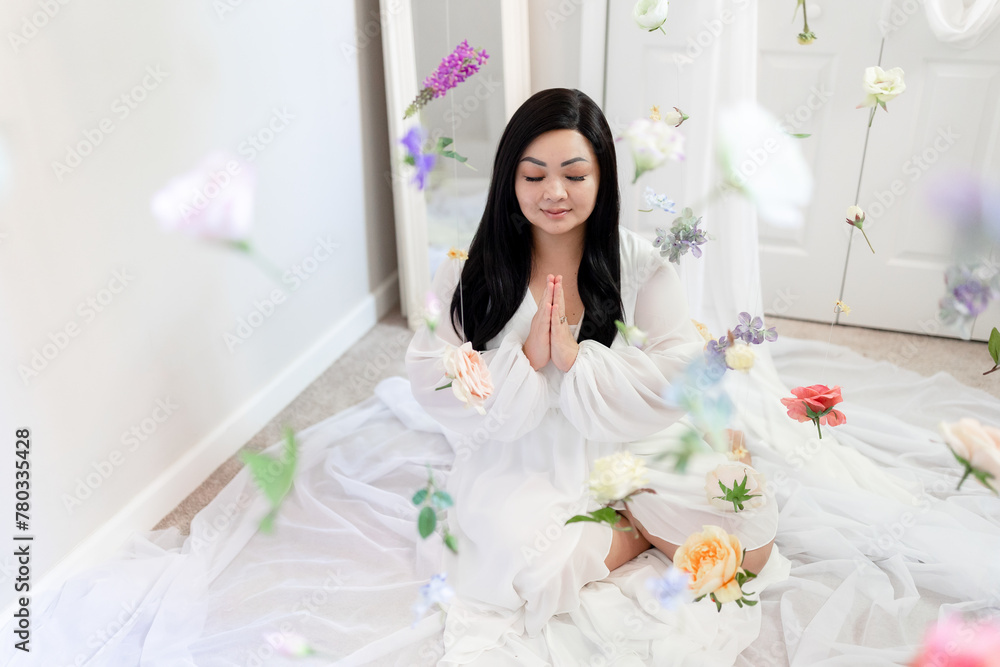 Zen asian woman meditating, praying, hanging flowers, bright whi Zen asian woman meditating, praying, hanging flowers, bright whi