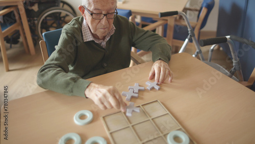 elderly man placing a board game tile in a retirement home photo